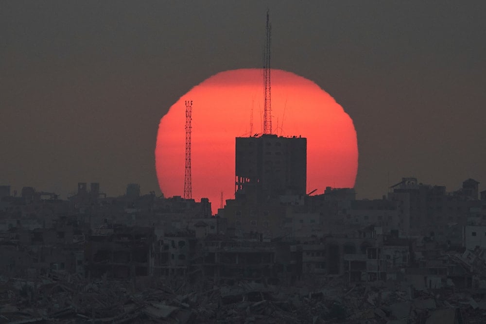 The sun sets over damaged buildings in the Gaza Strip, seen from southern Israel, Tuesday, July 1, 2025 (AP)