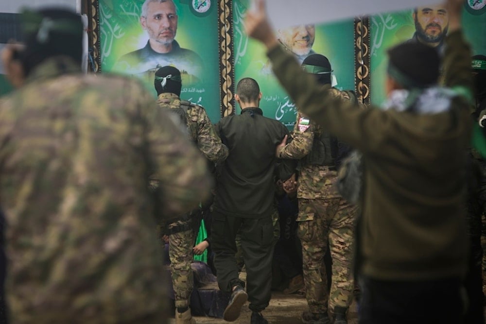 An Israeli captive is escorted by Hamas fighters before being handed over to the Red Cross in Nuseirat, central Gaza Strip, Saturday, February 22, 2025 (AP)