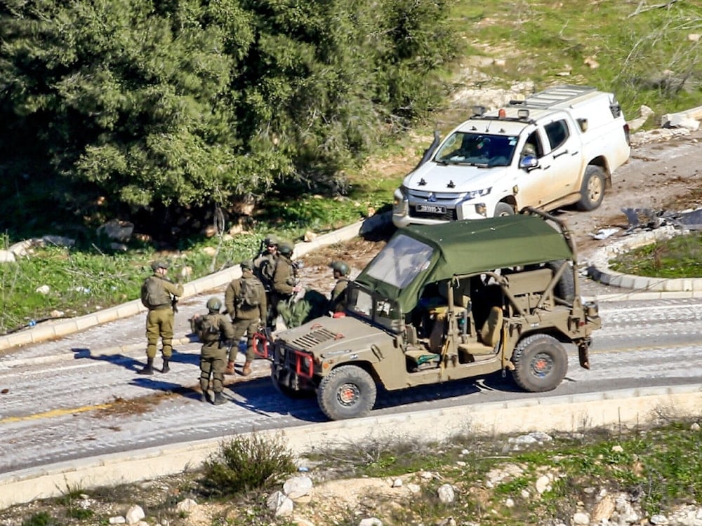 This picture taken from Lebanon's southern village of Shaqra on January 25, 2025 shows Israeli army soldiers by a humvee and a four-wheel-drive vehicle at the entrance of the village of Houla along the border with