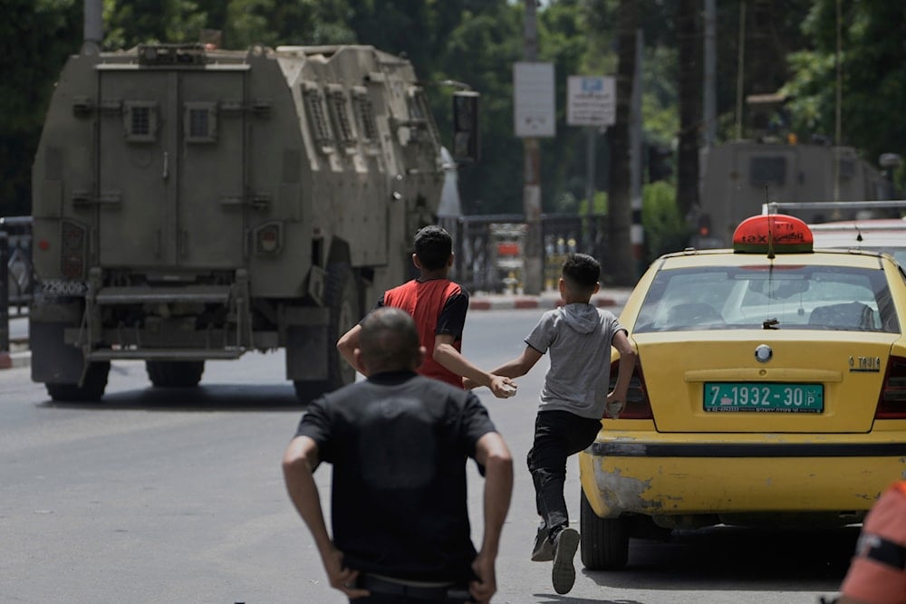 Young Palestinians prepare to throw stones at Israeli forces following a military raid in the West Bank city of Nablus, Tuesday, May 27, 2025 (AP)