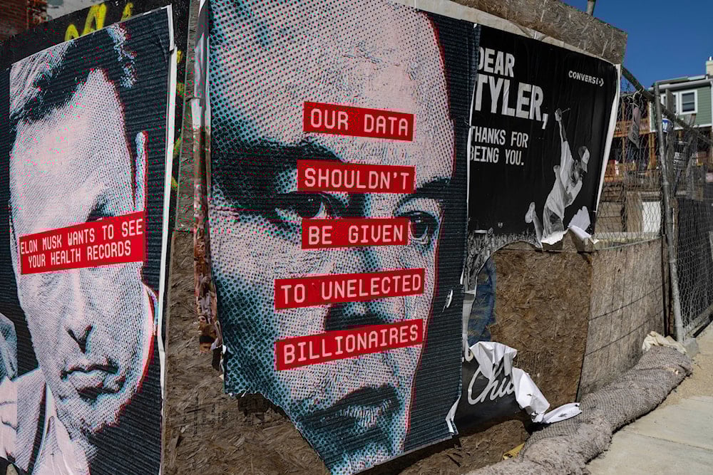 Posters showing the face of Elon Musk and messages relating to data privacy are seen on a fence surrounding a building site in Washington, Friday, March 7, 2025 (AP)