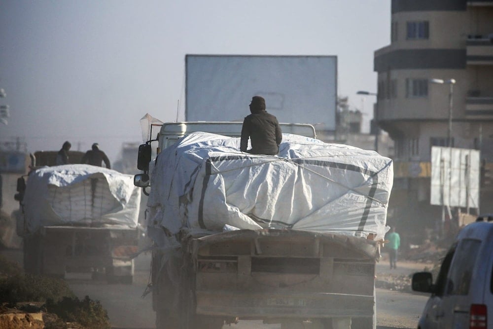 Men ride atop trucks loaded with aid as they travel through Deir el-Balah in central Gaza on Nov. 5.(Eyad Baba / AFP via Getty Images)