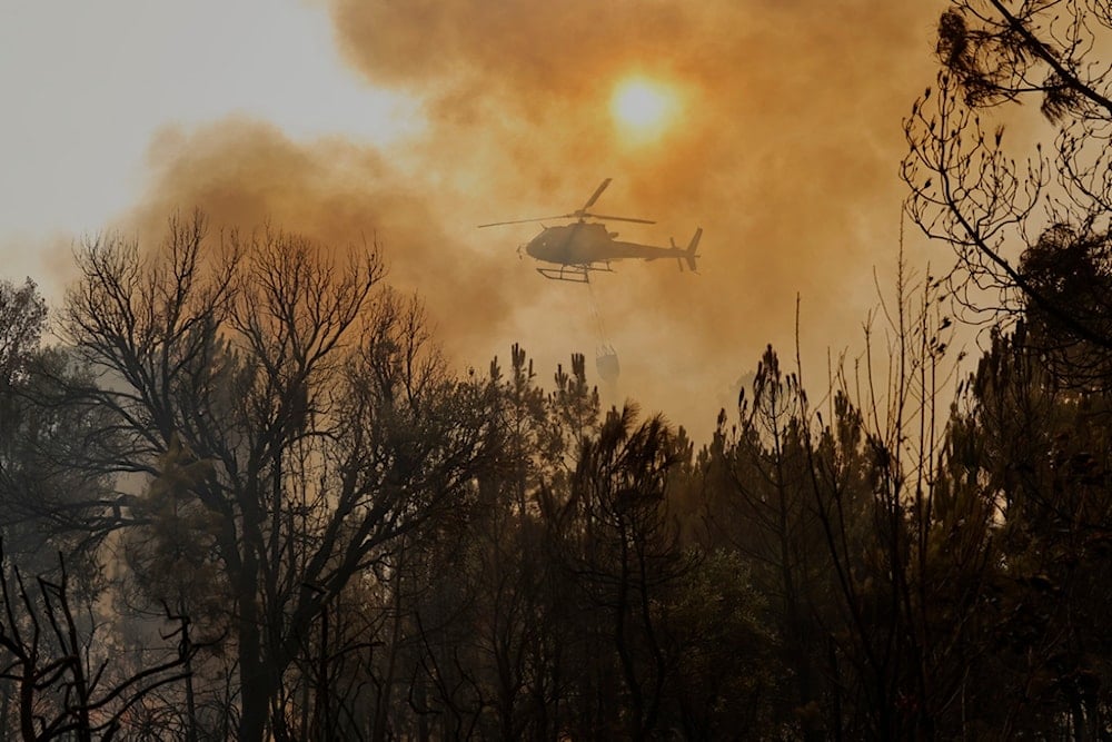 A helicopter drops water on a wildfire in Larouco, northwestern Spain, Wednesday, Aug. 13, 2025. (AP Photo/Lalo R. Villar)