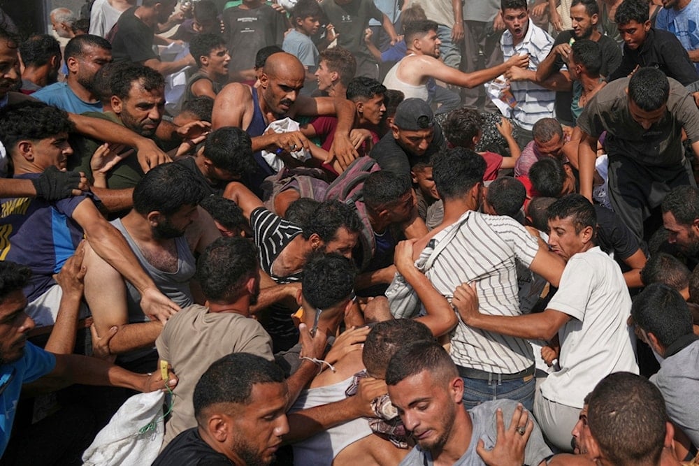 Palestinians struggle to collect humanitarian aid airdropped by parachutes into Gaza City, northern Gaza Strip, Thursday, August 14, 2025 (AP)