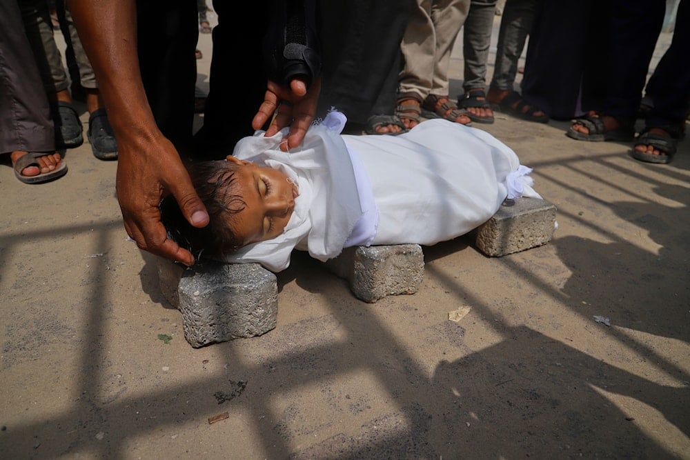 The body of 5-year-old Jamal al-Najjar is placed on the ground atop bricks before a funeral prayer after he died at Nasser Hospital in Khan Younis, southern Gaza Strip, on August 12, 2025.