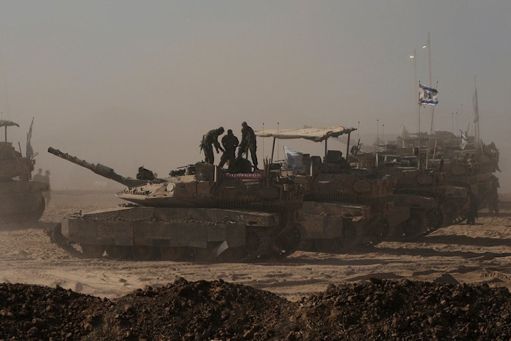 Israeli soldiers stand on the top of a tank parked in an area near the Gaza Strip, as seen from southern occupied Palestine, Monday, August 18, 2025 (AP)