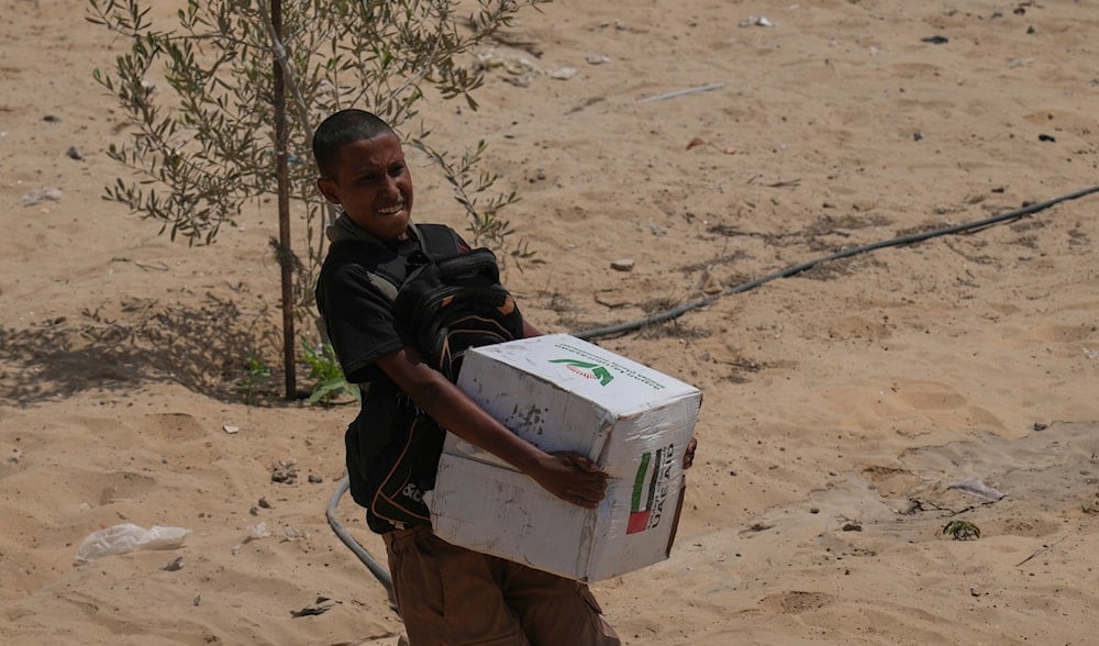 A Palestinian child collects humanitarian aid from the United Arab Emirates, airdropped by parachutes into Deir al-Balah, in the central Gaza Strip, Tuesday, Aug. 19, 2025. (AP)
