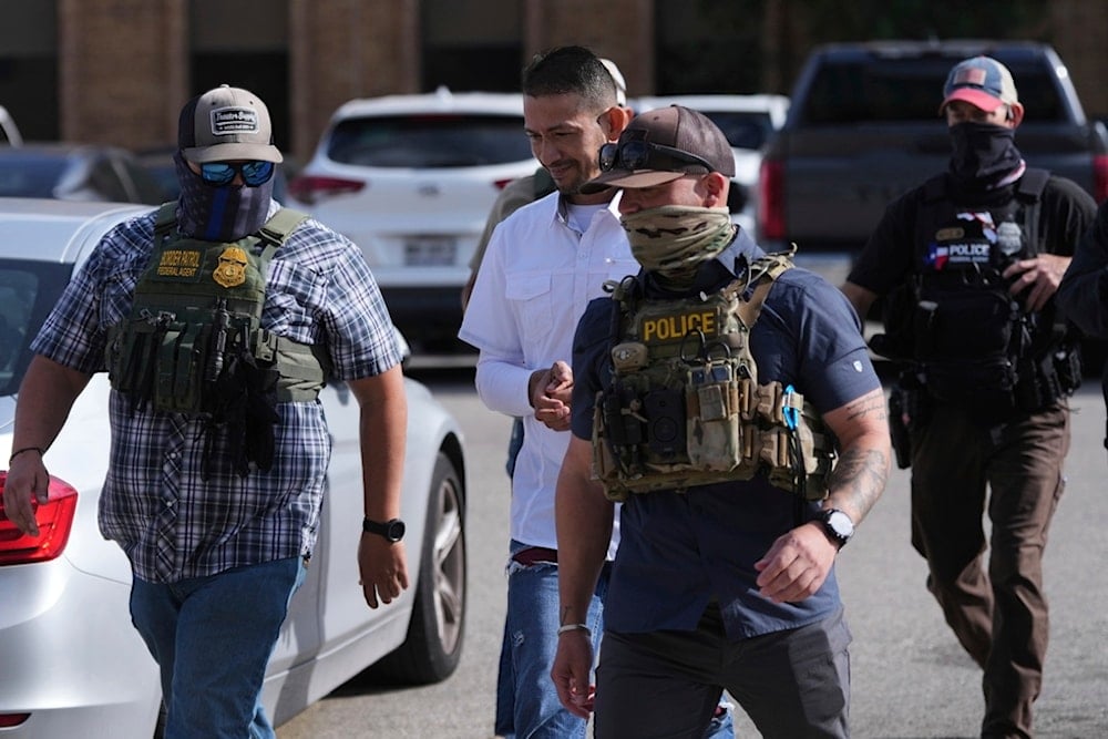 Federal agents escort a man to a transport bus after he was detained following an appearance at immigration court, Tuesday, July 22, 2025, in San Antonio. (AP Photo/Eric Gay)
