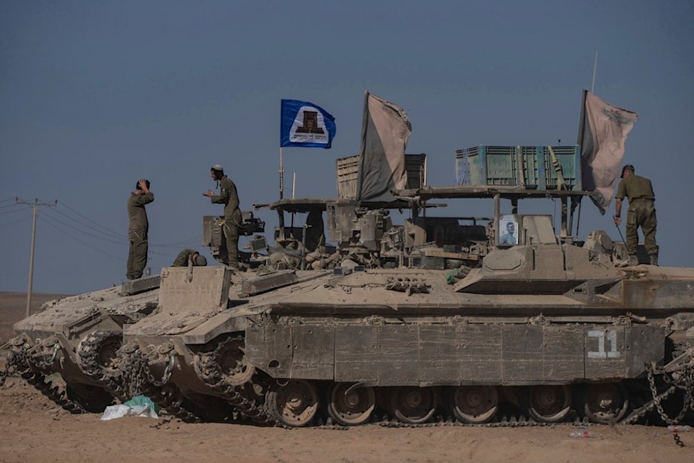 Israeli soldiers stand on the top of armoured vehicles parked in an area near the Gaza Strip, as seen from southern occupied Palestine, Wednesday, August 20, 2025 (AP)