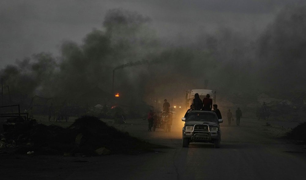 Palestinians ride their vehicles through black smoke from makeshift burners used to extract fuel from melted plastic along the Sea Road, at dusk in the south of Gaza City, Thursday, Aug. 21, 2025. (AP)