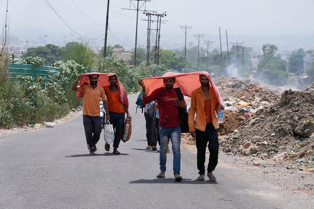 People cover their heads with scarves to protect themselves from the harsh sun on a hot summer day in Jammu, India, Tuesday, June 10, 2025  (AP)