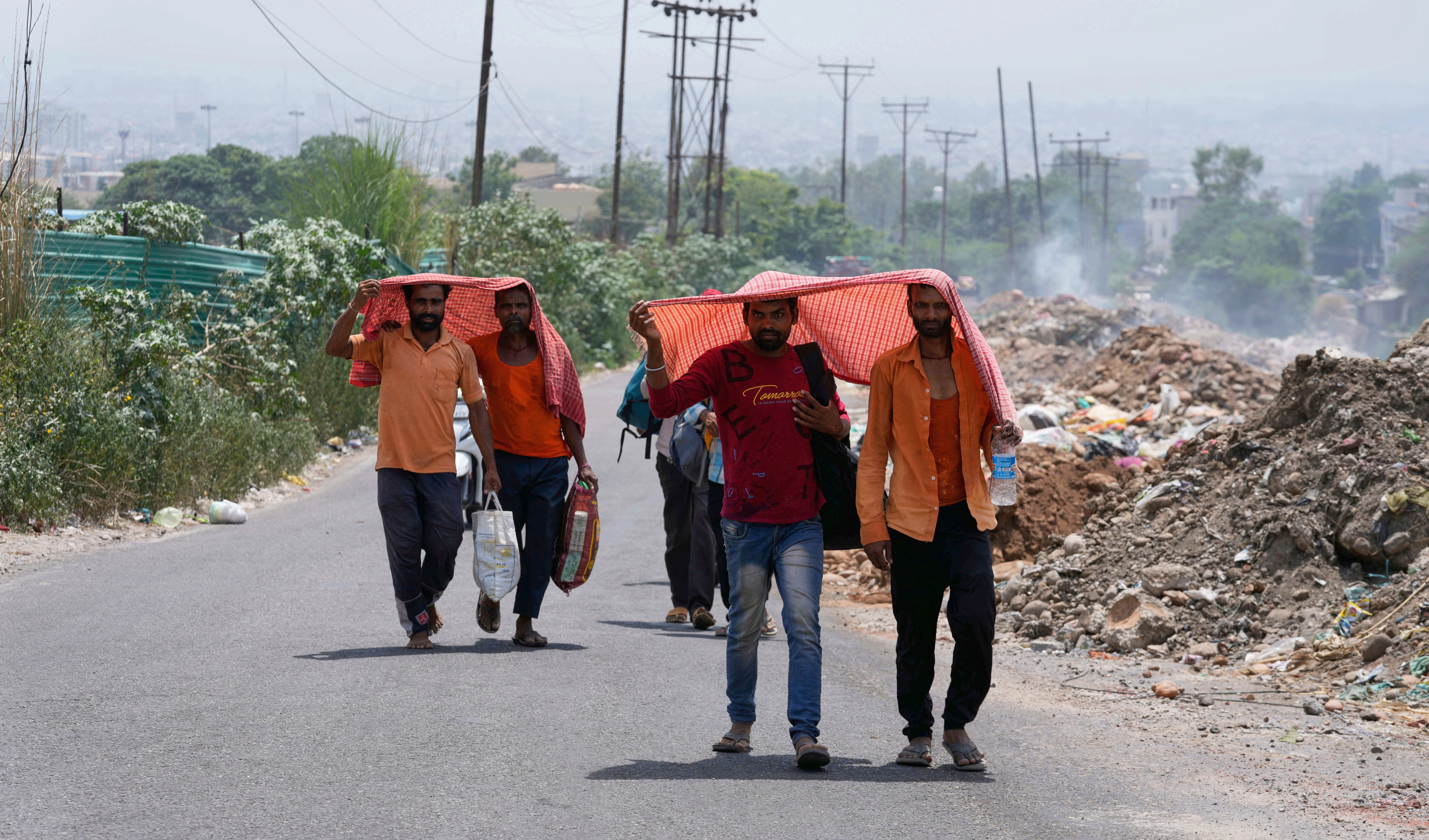 People cover their heads with scarves to protect themselves from the harsh sun on a hot summer day in Jammu, India, Tuesday, June 10, 2025  (AP)