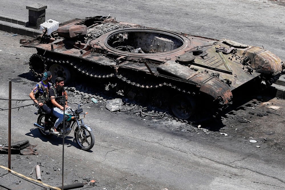 Druze militiamen ride a motorcycle past a destroyed military vehicle following last week's sectarian clashes in the Druze-majority town of Sweida, Syria, Friday, July 25, 2025 (AP)