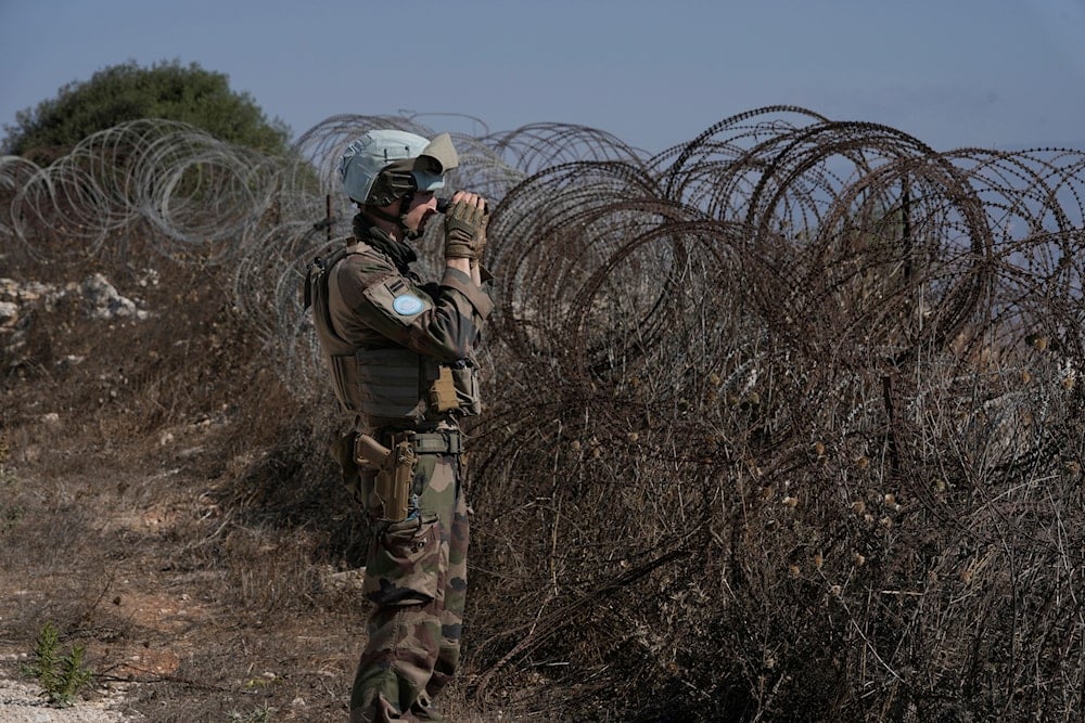 A French UN peacekeeper looks through binoculars while standing on a hill overlooking Kfar Kila, a Lebanese border village destroyed by Israeli airstrikes and a ground offensive, southern Lebanon, Wednesday, Aug. 20, 2025 (AP)