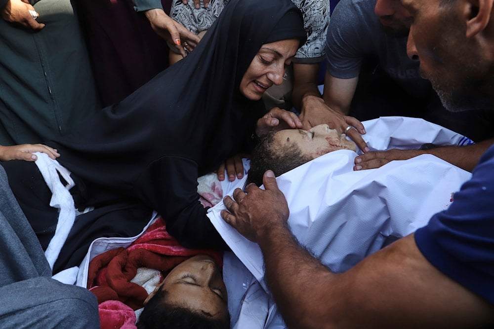 Palestinian Amna Foujo mourns over the bodies of her two children, Abdullah, 10, and Awad Foujo, 13, killed in overnight Israeli strikes, during their funeral outside Nasser Hospital in Khan Younis, southern Gaza Strip, Saturday, Aug. 23, 2025 (AP)