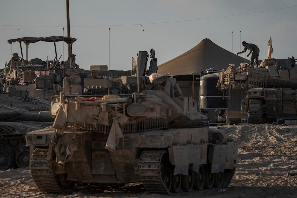 An Israeli soldier works on a tank parked in a staging area near the Israeli-Gaza border, Occupied Palestine, Thursday, Aug. 21, 2025 (AP)