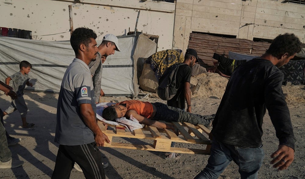 Palestinians carry the body of a boy who was killed while trying to reach a humanitarian aid convoy on the outskirts of Beit Lahia, as they walk on a road in Gaza City, in the Gaza Strip, Sunday, Aug. 24, 2025. (AP)