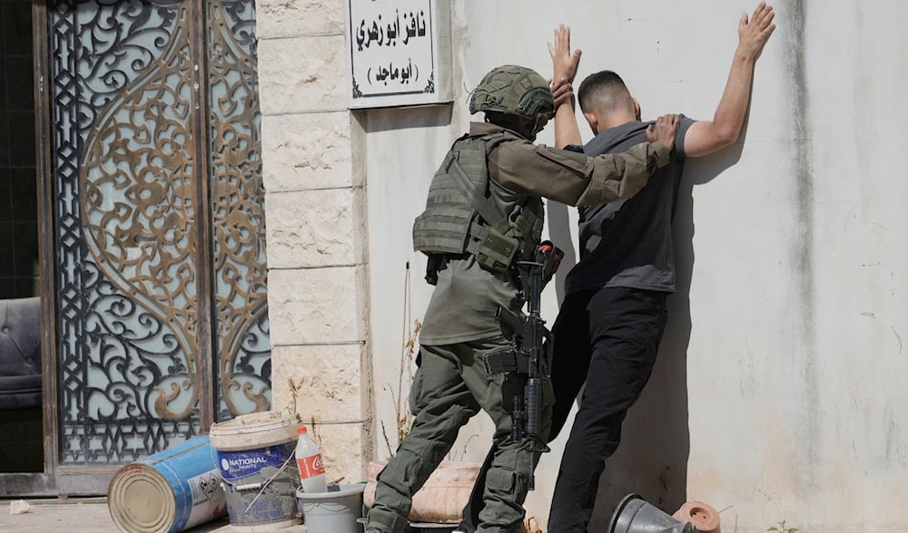 An Israeli soldier body search a Palestinian man in the West Bank refugee camp of Tulkarm, Sunday, July 6, 2025. (AP)