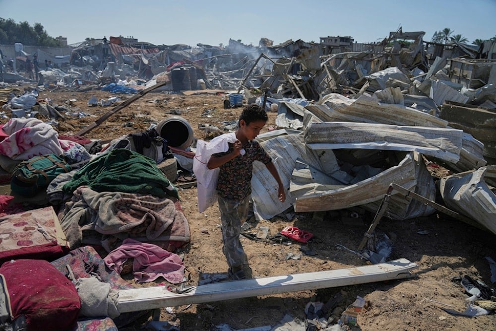 A Palestinian boy walks amid debris after Israeli military strikes in a tent camp for displaced people near al-Aqsa Hospital, in Deir al-Balah, Thursday, August 21, 2025 (AP)
