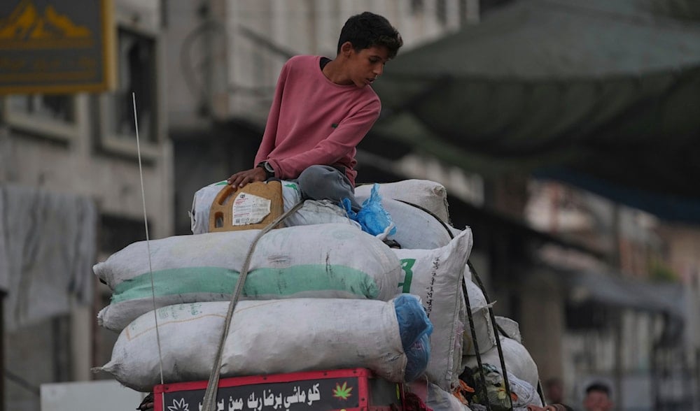 Displaced Palestinians fleeing Jabalia move with their belongings on a street in Gaza City, Tuesday, Aug. 26, 2025. (AP Photo/Jehad Alshrafi)