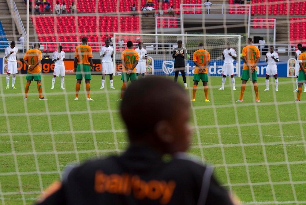 A ball boy looks at Zambia's national team players and Sudan's national team player as they stand, at the start of the African Cup of Nations quarter finals soccer match in Bata, Equatorial Guinea, Saturday, Feb. 4, 2012 (AP)