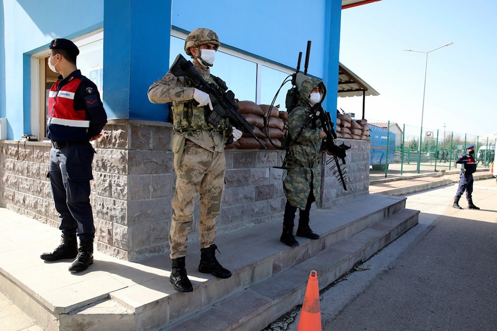 Soldiers stand in guard as people wait outside a courthouse before the trial of 497 defendants, in Sincan, outside the capital Ankara, Turkey, Wednesday, April 7, 2021 (AP)