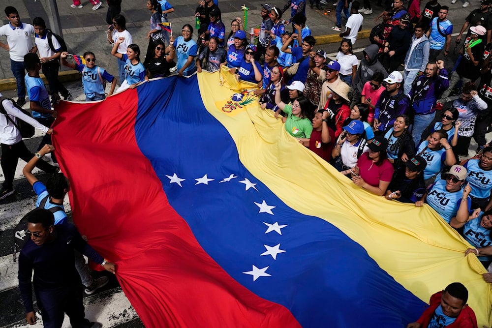 Government supporters hold out a Venezuelan flag during a march on Youth Day in Caracas, Venezuela, Wednesday, Feb. 12, 2025 (AP)
