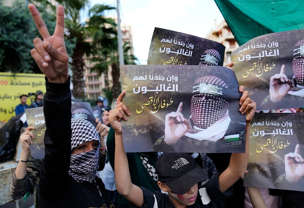 A Palestinian protester flashes victory sign, as other hold up portraits of Abu Obeida, the spokesman for the Qassam Brigades, the Hamas' military wing, during a protest in Beirut, Lebanon, November 18, 2025 (AP)