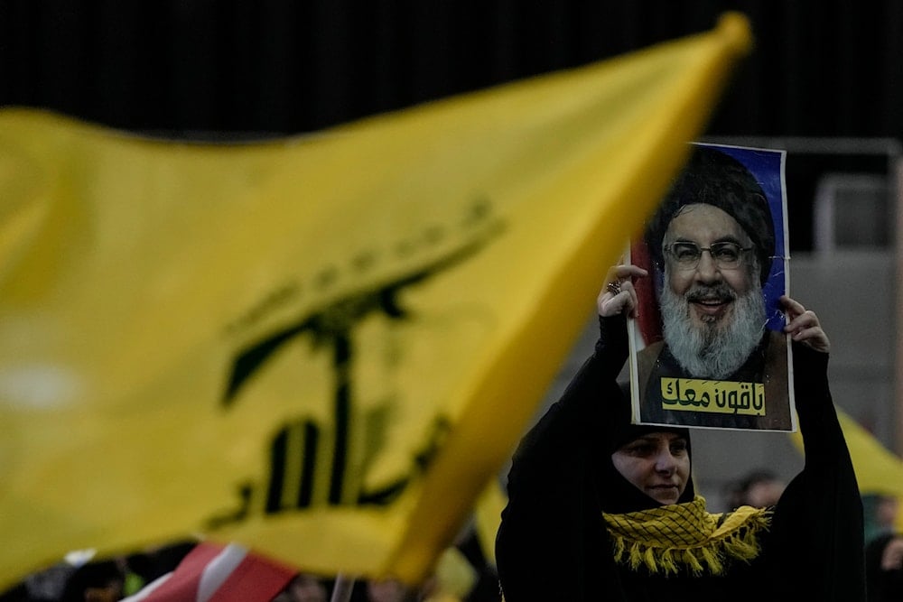 A Supporter of Hezbollah holds up a portrait of Hezbollah late leader Sayyed Hassan Nasrallah with Arabic words reading: 
