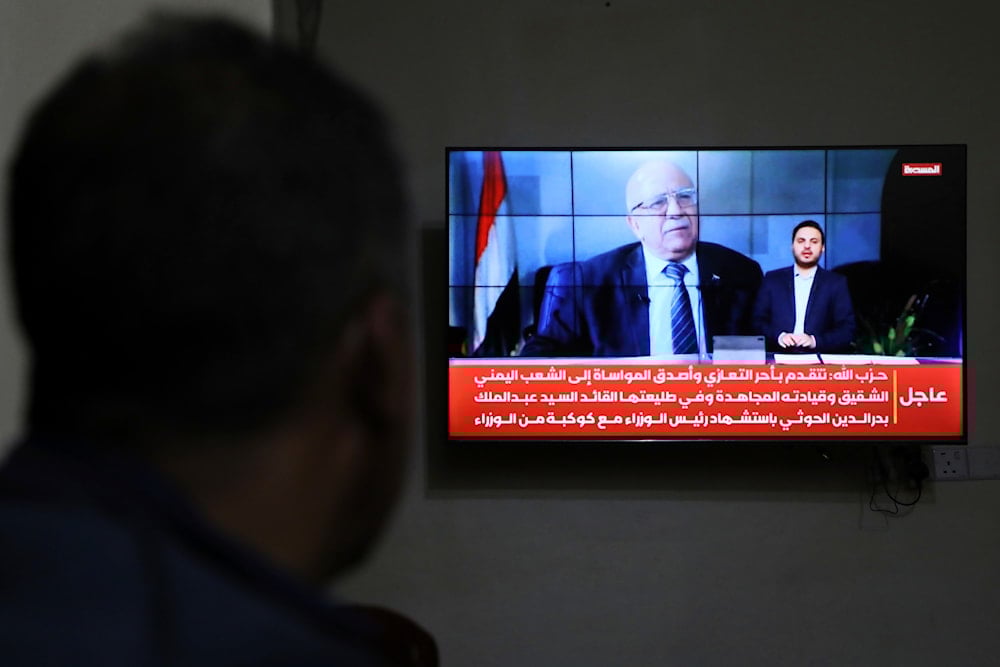 A man watches the news on TV, displaying footage of Ahmed al-Rahawi, the prime minister of the Yemeni government, who was killed, along with others, in Thursday's Israeli strikes on the capital, in Sanaa, Yemen, Saturday, Aug. 30, 2025 (AP)