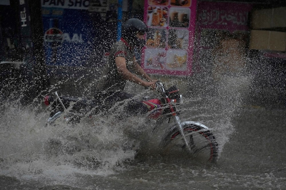 Motorists ride through a flooded road caused by heavy monsoon rain in Lahore, Pakistan, Sunday, August 3, 2025. (AP Photo/K.M. Chaudary)
