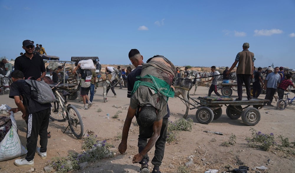 A Palestinian carries the body of a man killed while trying to receive aid near a distribution center operated by the U.S.-backed Gaza Humanitarian Foundation (GHF) in Netzarim, in the Gaza Strip, Monday, Aug. 4, 2025. (AP)