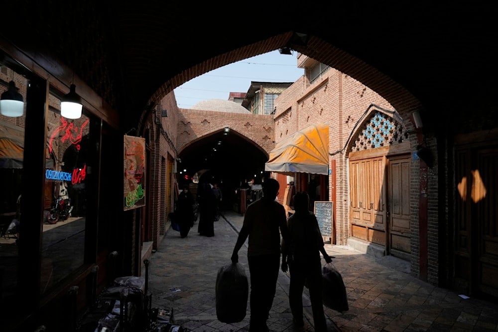 People carry their shopping at the historic neighborhood of Oudlajan in Tehran, Iran, Thursday, July 31, 2025 (AP)