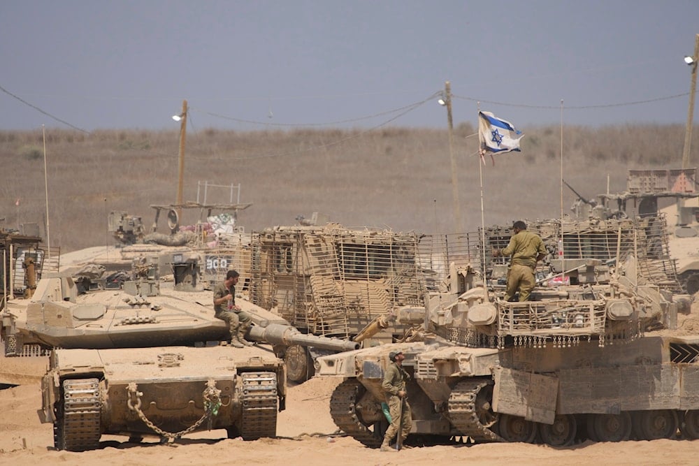 Israeli soldiers work on their tanks in a staging area near the Gaza Strip, Occupied Palestine, Tuesday, July 29, 2025 (AP)