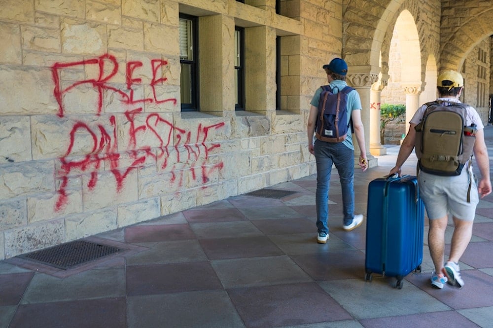 Students walk by graffiti near university president Richard Saller's office at Stanford University in Palo Alto, California, Wednesday, June 5, 2024 (AP)