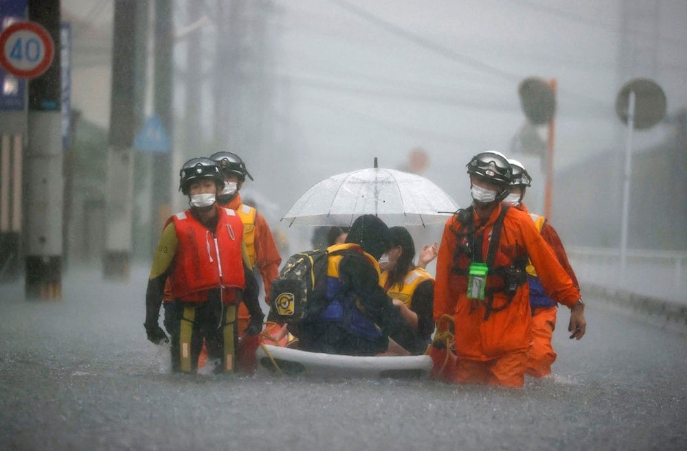 Firefighters carry stranded residents on boat in a road flooded by heavy rain in Kurume, Fukuoka prefecture, western Japan, on August 14, 2021. 