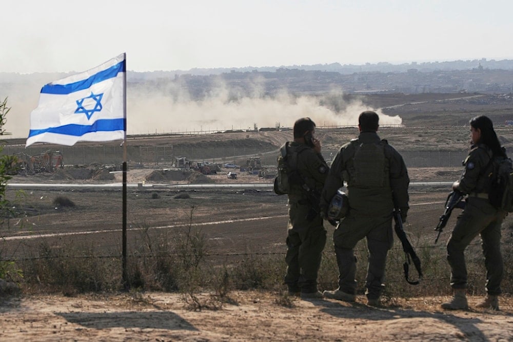 Israeli soldiers watch the northern Gaza Strip from southern occupied Palestine, Wednesday, July 30, 2025 (AP)  