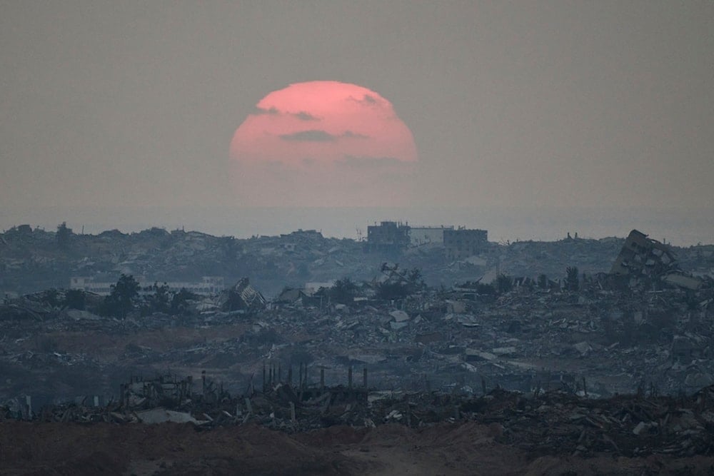 The sun sets behind buildings that were destroyed during the Israeli ground and air offensive, standing in the northern Gaza Strip as seen from southern occupied, Friday, August 8, 2025 (AP)