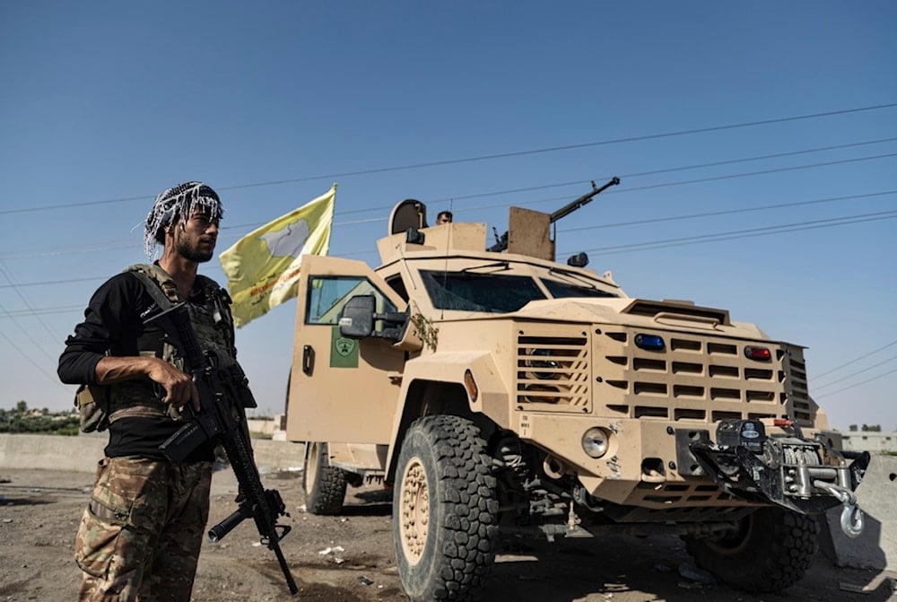 A US-backed Syrian Democratic Forces (SDF) fighter stands next an armored vehicle, at al-Sabha town in the eastern countryside of Deir el-Zour, Syria, Monday, Sept. 4, 2023. 