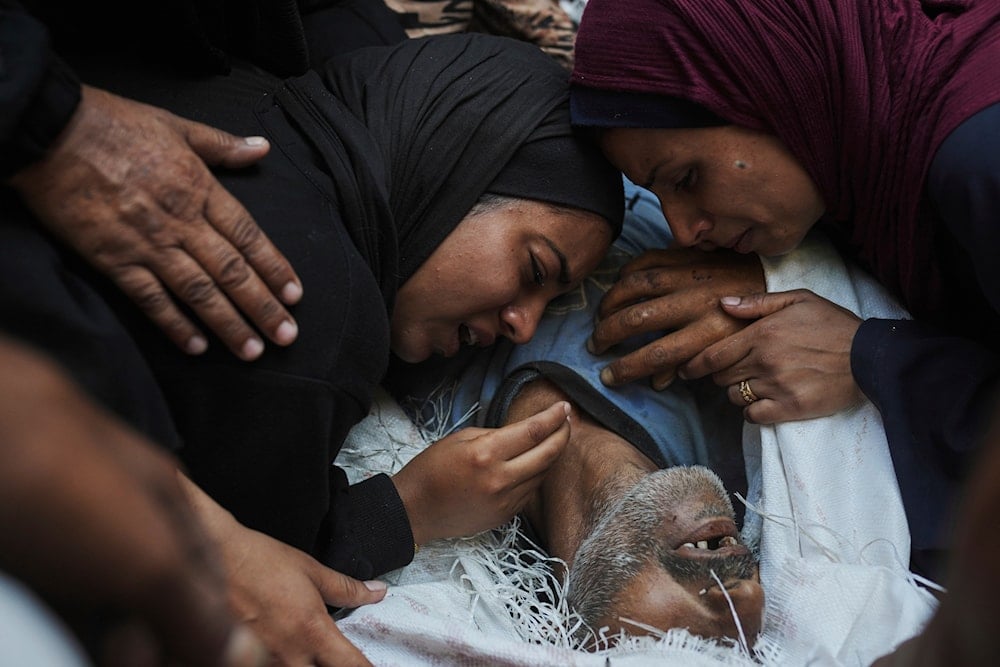 Palestinian women mourn over the body of their father, who was killed while trying to reach aid trucks entering northern Gaza Strip through the Zikim, Gaza City, Occupied Palestine, Monday, Aug. 4, 2025 (AP)
