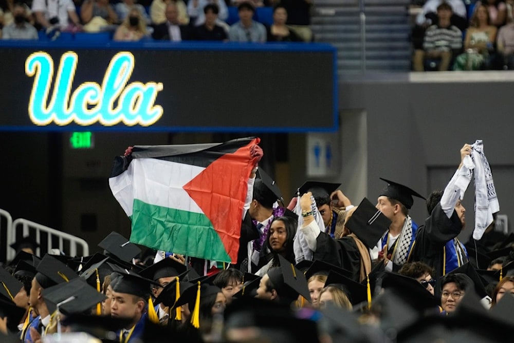 UCLA graduating students wave a Palestinian flag during the commencement ceremony inside Pauley Pavilion on the UCLA campus, in Los Angeles, Friday, June 14, 2024 (AP)
