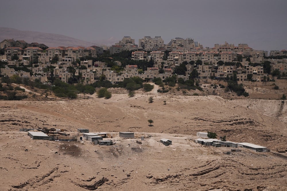 Makeshift houses of the Palestinian Bedouin Jahalin community, bottom, are seen next to the West Bank Israeli settlement of Maale Adumim, Occupied Palestine, Monday, June 2, 2025 (AP)