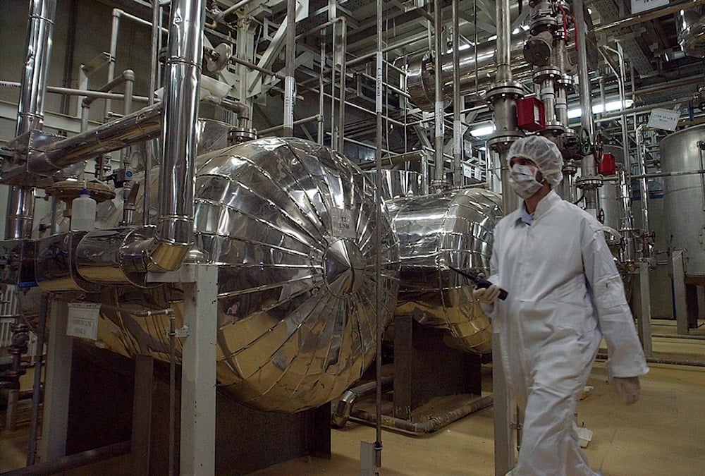 An Iranian security official in protective clothing walks through part of the Uranium Conversion Facility just outside the Iranian city of Isfahan, March 30, 2005. (AP)