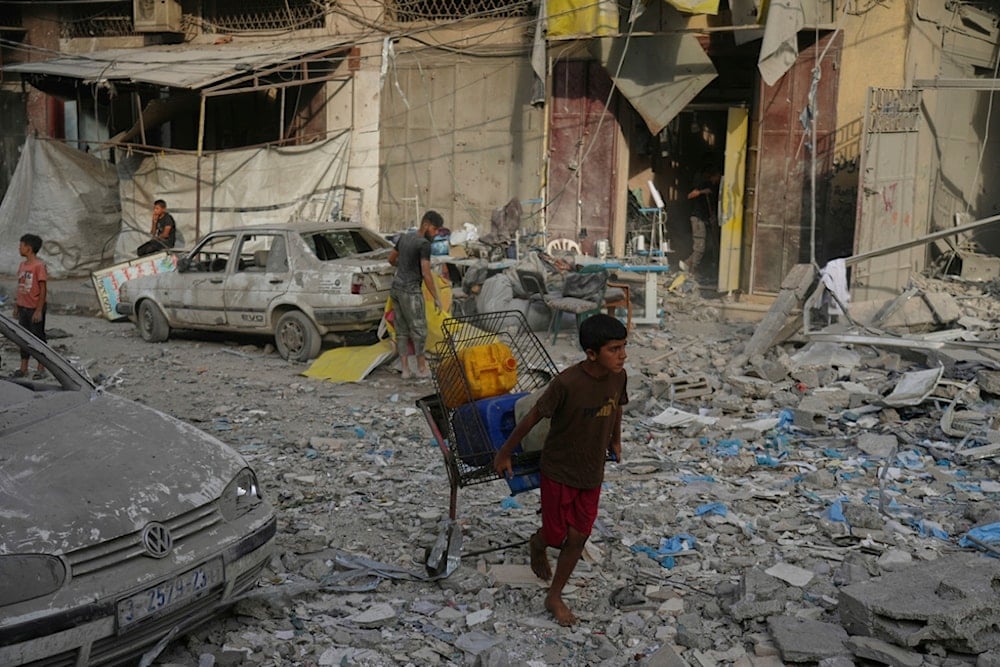 Carrying plastic jerrycans, a Palestinian boy walks past a heavily damaged building in the Rimal neighborhood, in Gaza City, Sunday, August 31, 2025. (AP)