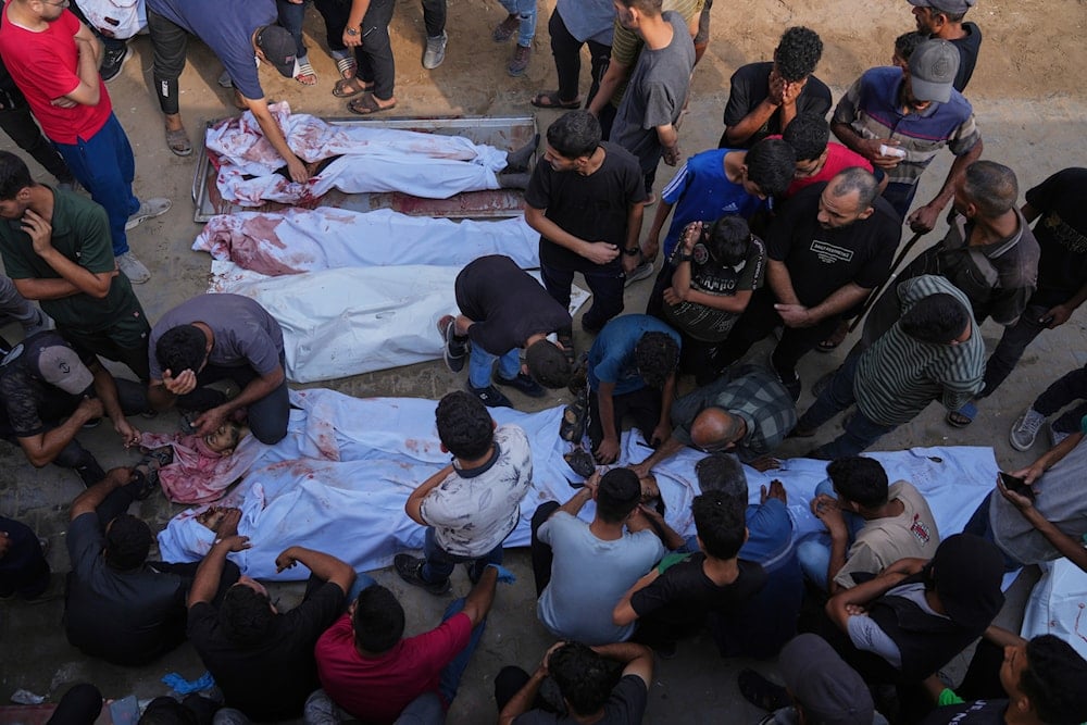Palestinians mourn over the bodies of people killed either by Israeli military strikes or while trying to reach aid trucks, outside Shifa Hospital in Gaza City, on August 31, 2025. (AP Photo/Jehad Alshrafi)