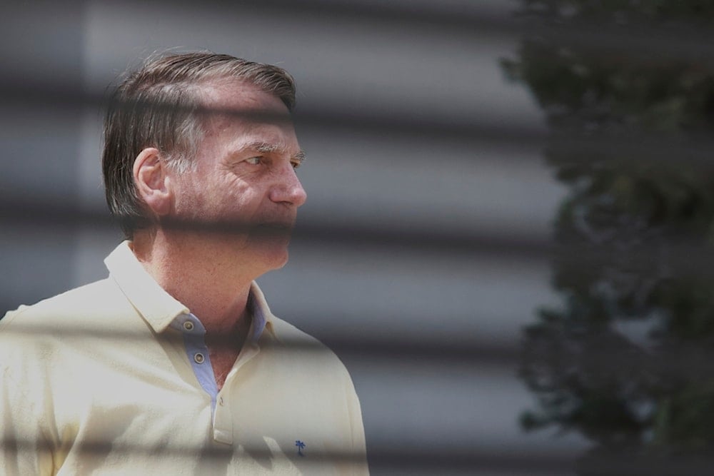 Brazil's former President Jair Bolsonaro stands behind the entrance gate of his home where he is under house arrest in Brasilia, Brazil, Wednesday, Sept. 3, 2025. (AP Photo/Luis Nova)