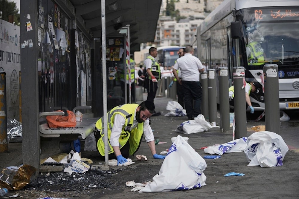 Israeli ZAKA rescue and recovery personnel clean bloodstains at the scene of a shooting operation at a bus stop in occupied al-Quds, Monday, September 8, 2025 (AP)