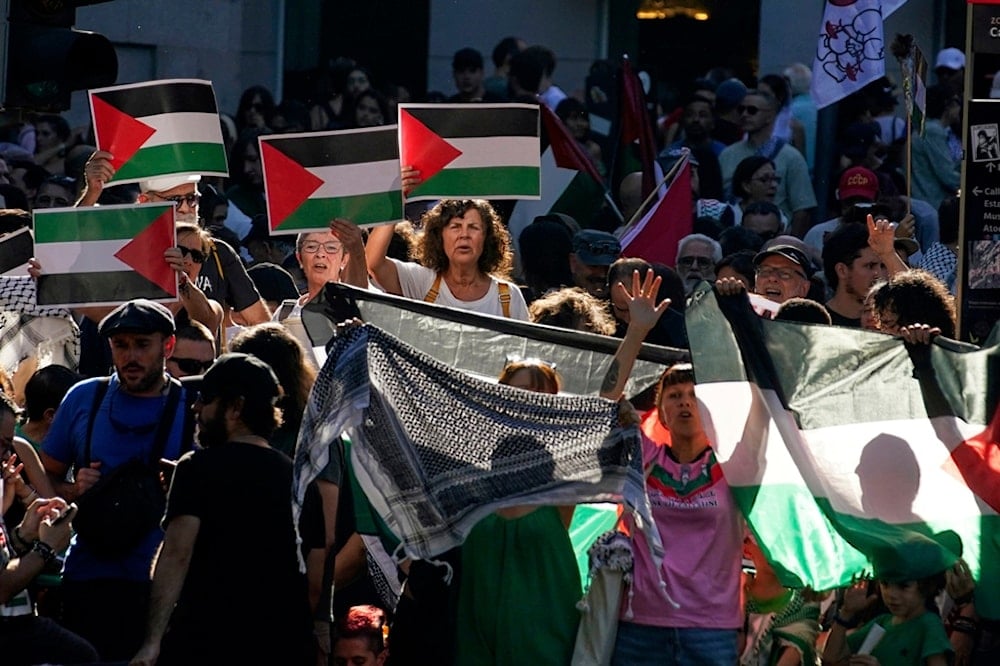 People shout slogans and hold Palestinian flags while protesting during the twenty-first stage of La Vuelta cycling race from Alalpardo to Madrid, Spain, Sunday, Sept. 14, 2025. (AP)