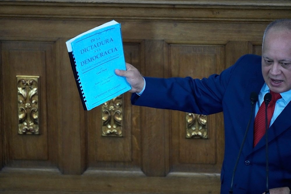 Venezuelan Minister of Interior, Justice and Peace Diosdado Cabello holds a copy of a book whose title reads in Spanish, 