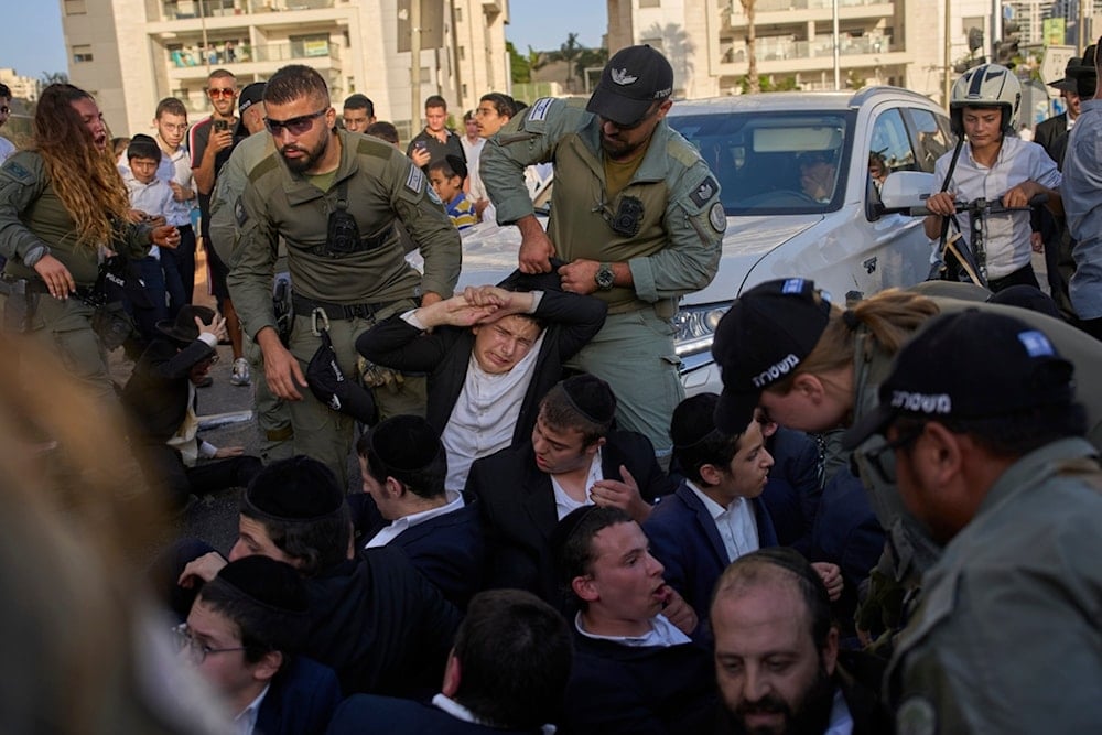 Police disperse ultra-Orthodox Jews blocking a highway during a protest against army recruitment, in Bnei Brak, Israel, Tuesday, August 19, 2025. (AP Photo/Ohad Zwigenberg)